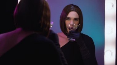 Soyunma odasında kokteyl içen şık drag queen, hayattan memnun