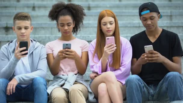 Adolescente grupo de amigos sentados em escadas e conversando smartphone, vício — Vídeo de Stock