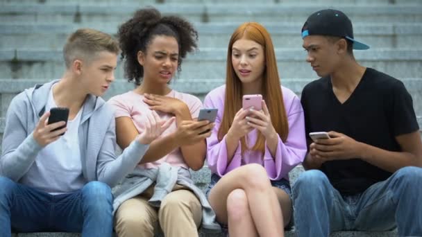 Пристрастившиеся к технологиям друзья-подростки используют мобильные телефоны вместе, фото не любят — стоковое видео