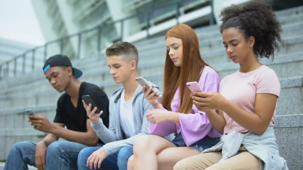 Мультиэтнические друзья-подростки используют смартфон вместе, отсутствие общения — стоковое видео