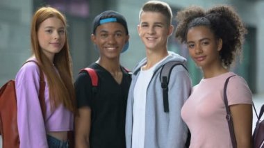Sırt çantaları ile çok ırklı öğrenci grubu thumbs-up, eğitim gösteren