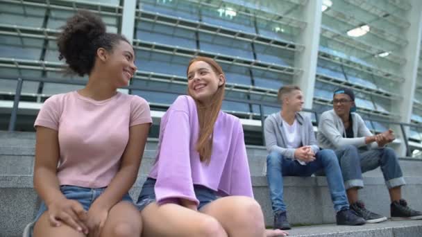 Tini fiúk és lányok nevetve, külön ül az iskolában stadionban, kényelmetlen életkor — Stock videók