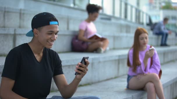 Emocionado estudiante negro leyendo el mensaje del teléfono inteligente que muestra sí gesto, éxito — Vídeo de stock