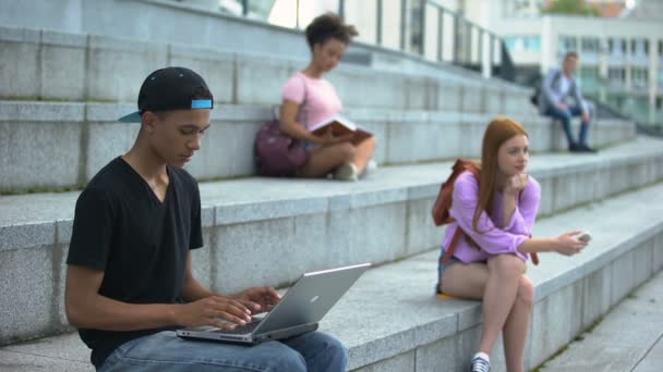 Jeune étudiant tapant ordinateur portable assis campus escaliers, génération numérique, freelance — Video