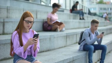 Kampüste merdivenoturan akıllı telefon mesajı yazarak gözlük üzgün kız öğrenci