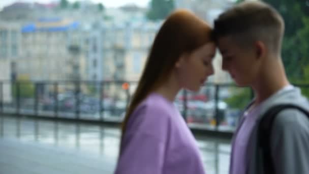 Pareja joven mirando unos a otros en el fondo de la ciudad de lluvia tocando frentes — Vídeos de Stock