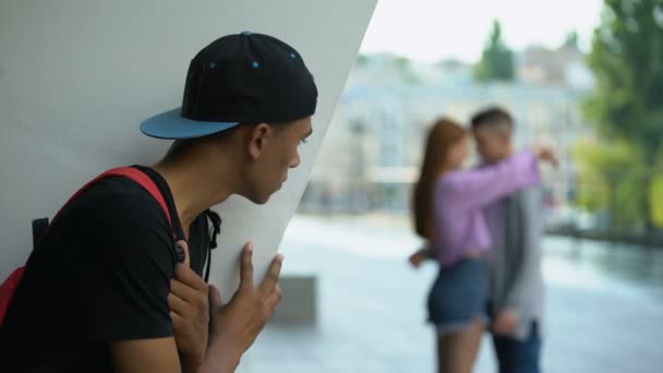 Disappointed african teenager looking female hugging classmate, unrequited love — Stock Video