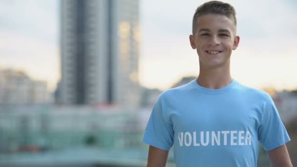 Joyeux lycéen en t-shirt volontaire caméra souriante, aide humanitaire — Video