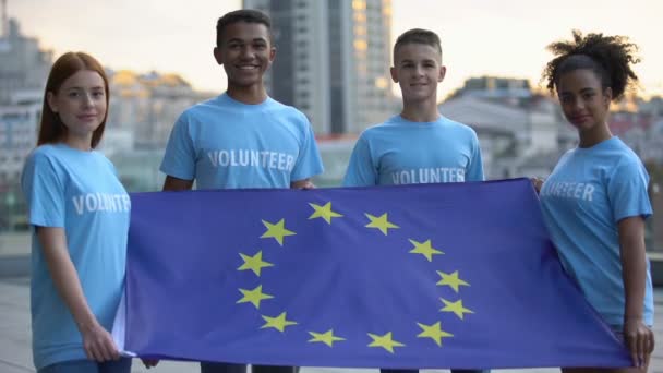 Jóvenes voluntarios multirraciales con bandera de la Unión Europea, unidad internacional — Vídeo de stock
