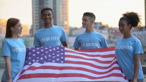 Heureux bénévoles multi-raciaux tenant drapeau américain, fondation caritative, aide — Video