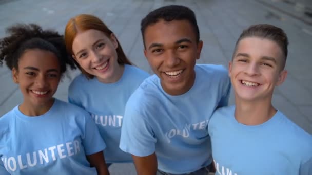 Freudige College-Studenten in freiwilligen T-Shirts suchen Kamera, unterstützen das Miteinander — Stockvideo