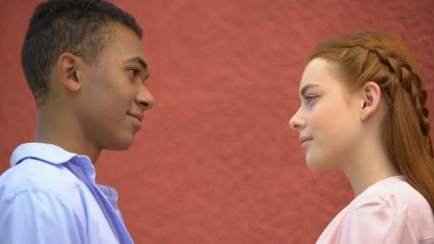 Par de amantes adolescentes timidamente olhando nos olhos uns dos outros, movendo-se de perto — Vídeo de Stock