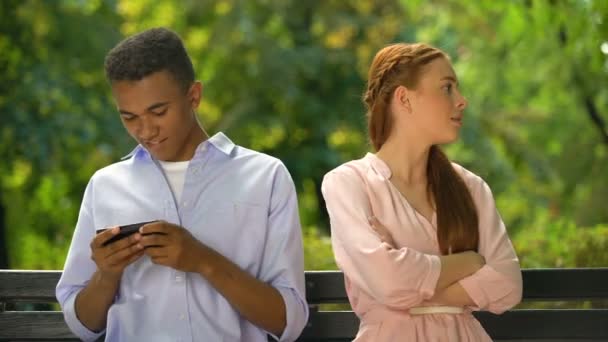 Mixed-race boy ignoring girlfriend playing games on smartphone, addiction — Stock Video