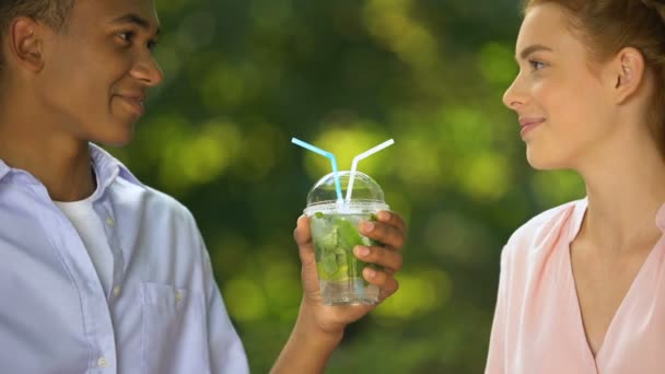 Young couple of students drinking beverage looking at each other with love — Stock Video