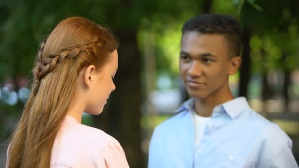 Blyg Afro-American boy presentera bukett blommor till leende flicka i parken — Stockvideo
