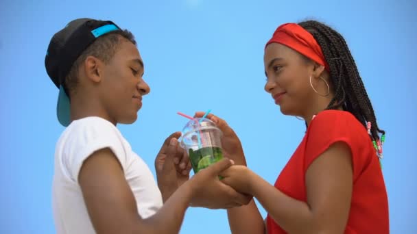 Coppia multietnica innamorata che beve bicchiere di cocktail fresco attraverso due cannucce — Video Stock