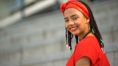 Kameraya gülümseyen örgüler ile güzel karışık ırk kız, şık gençlik, moda