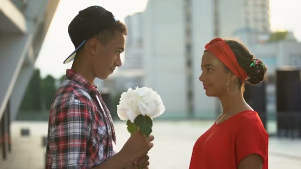 Подросток дарит цветы красивой девушке, испытывает первую любовь, романтику — стоковое видео