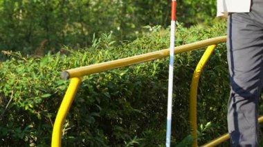 Baston yardımı ile parkta tezgah arayan görme bozukluğu olan olgun adam