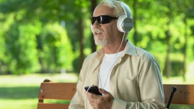 Görme engelli kıdemli adam zevk, kulaklık müzik dinlerken