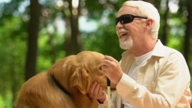 Görme engelli park rehberi köpek petting ile Kind adam, parkta bankta oturan