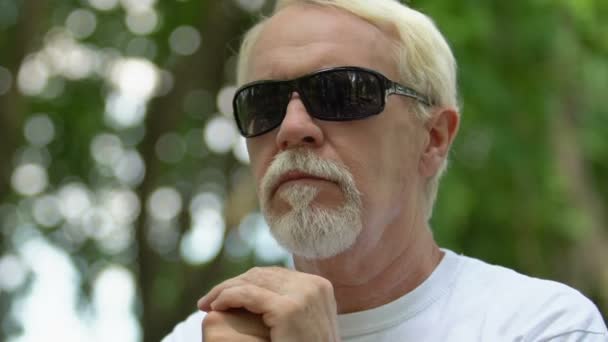 Retired man with visual impairment resting on bench in park leaning on cane — Stock Video