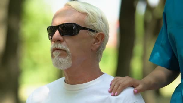 Female medical worker putting hand on blind man shoulder, supporting him, aid — Stock Video