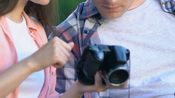 Γυναίκα φωτογράφος που εμφανίζει εικόνες στην οθόνη της κάμερας σε νεαρό άνδρα, συμβουλές χόμπι — Αρχείο Βίντεο