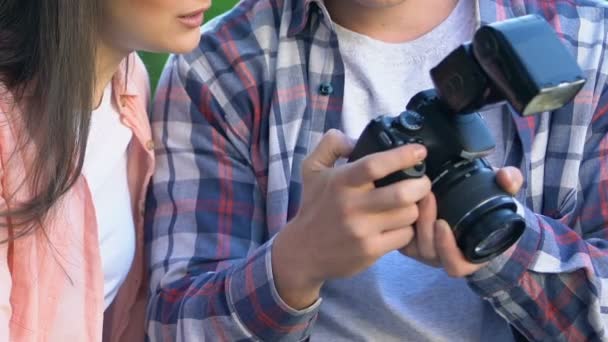 Мужской фотограф показывает фотографии с экрана на женщину, творческая профессия — стоковое видео