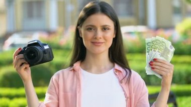 Gülümseyen güzel kadın tutan kamera ve euro banknotlar, fotoğrafçı maaş