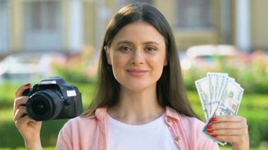 Mutlu kadın fotoğrafçı kamera ve dolar tutan, hobi kazanç, gelir