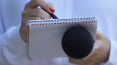 Mikrofon tutan notlar yazan kadın muhabir, özel röportaj