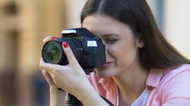 Молодая женщина калибрует объектив камеры, фотографирует на открытом воздухе, фотожурналист — стоковое видео