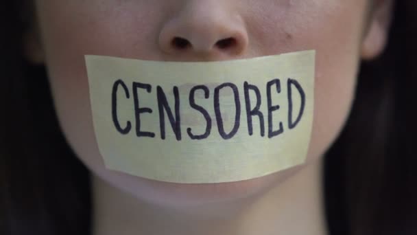 Censored written on tape, woman removing mouth sticker, speech freedom, pressure — ストック動画