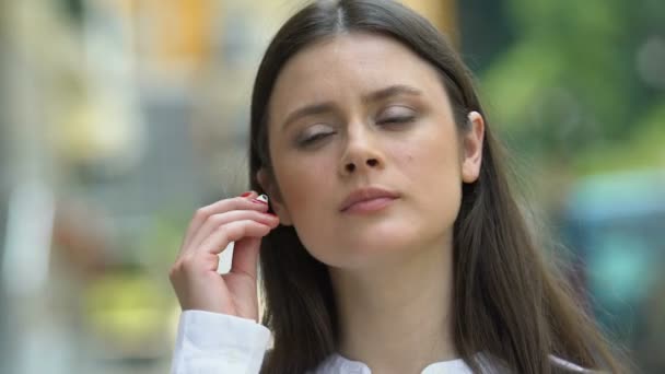 Mulher atraente usando fones de ouvido sem fio ouvindo música, desfrutando de som — Vídeo de Stock