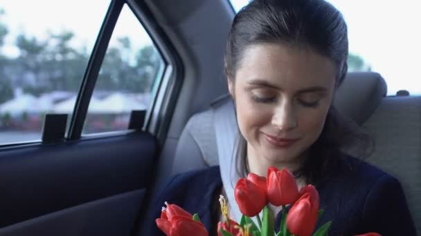 Menina feliz cheirar flores sentado no carro, cliente de táxi satisfeito desfrutando passeio — Vídeo de Stock