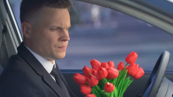Молодой человек бросает цветы в машину, подавленный после разрыва с девушкой — стоковое видео