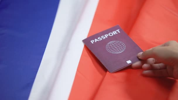 Mano femenina poniendo pasaporte rojo internacional en bandera francesa, ciudadanía — Vídeos de Stock