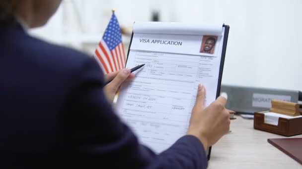 ビザ申請を承認する入国管理官、テーブルの上のアメリカの旗、観光 — ストック動画