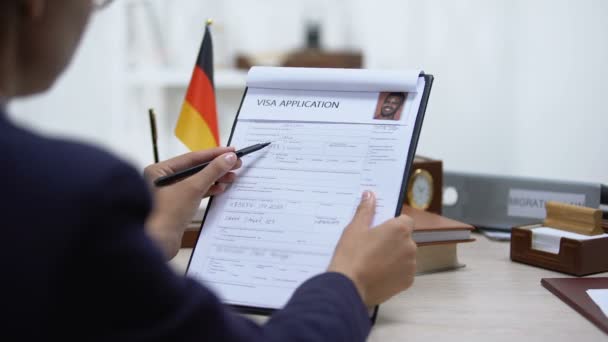 Сотрудник посольства одобряет заявление на визу, германский флаг на столе, полномочия — стоковое видео