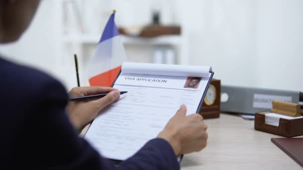 Employé de l'ambassade approuvant la demande de visa, drapeau français sur la table, loi sur la migration — Video