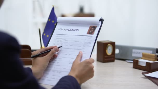 Empleado de la embajada que aprueba la solicitud de visa, bandera de la Unión Europea sobre la mesa, ley — Vídeo de stock