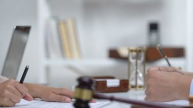 Kadın mahkeme salonunda belgeleri imzalıyor, noterle el sıkışıyor, hizmet veriyor.