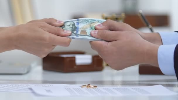 Мужчина и женщина тянут доллары, политика развода и обручальное кольцо на столе — стоковое видео