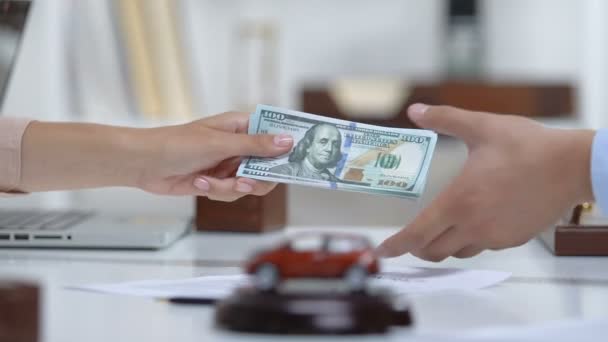 Vrouw koper geven Auto Trader dollars, handen schudden, auto speelgoed op tafel — Stockvideo