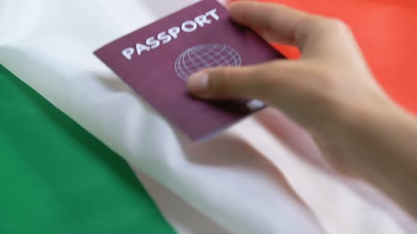 Persoon die rood paspoort op de Italiaanse vlag achtergrond, burgerschap status — Stockvideo