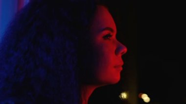 Young smiling woman watching night city lights enjoying home party, relaxing