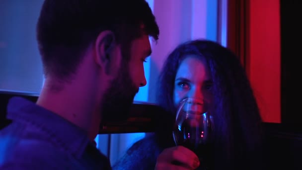 Joven hombre y mujer riendo bebiendo vino, divirtiéndose en la fiesta nocturna juntos — Vídeos de Stock
