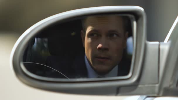 Vizsgáló üzletember keres külső autó, hátsó tükörképe, gyanú — Stock videók