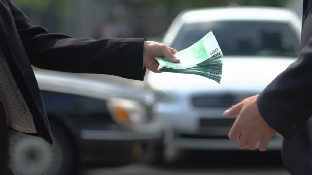 Mujer dando euros al hombre y estrechando la mano sobre el fondo de los coches, contrato de alquiler — Vídeos de Stock